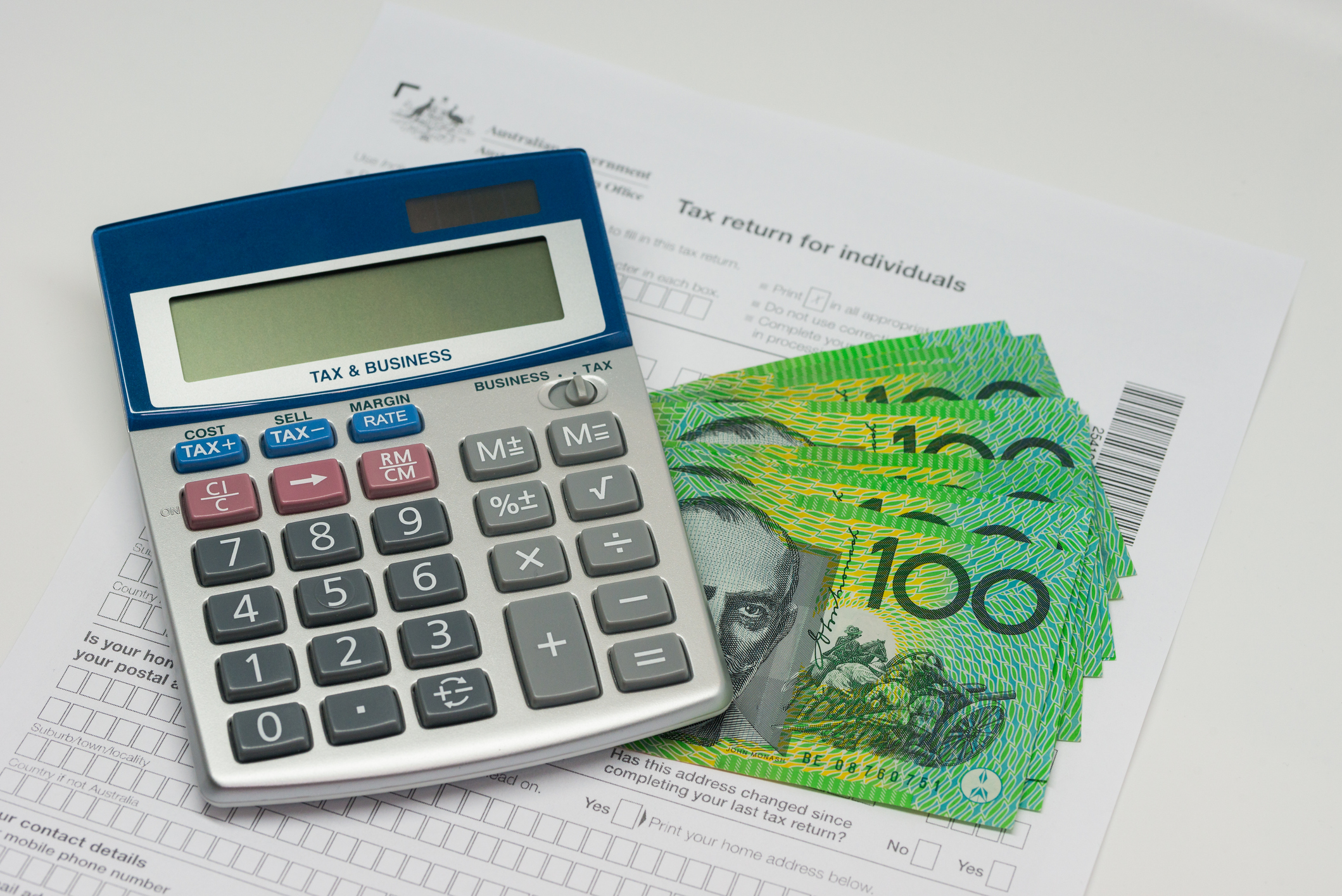 Calculator, Australian dollar banknotes and tax return form representing tax time and tax refunds in Australia.