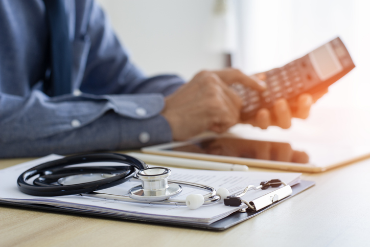 Healthcare professional reviewing work-related expenses with a calculator and stethoscope for Australian medical professional tax deductions and the 2025–26 tax return.