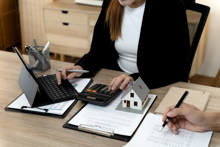 Property investor reviewing rental property expenses and financial documents with a calculator and laptop.