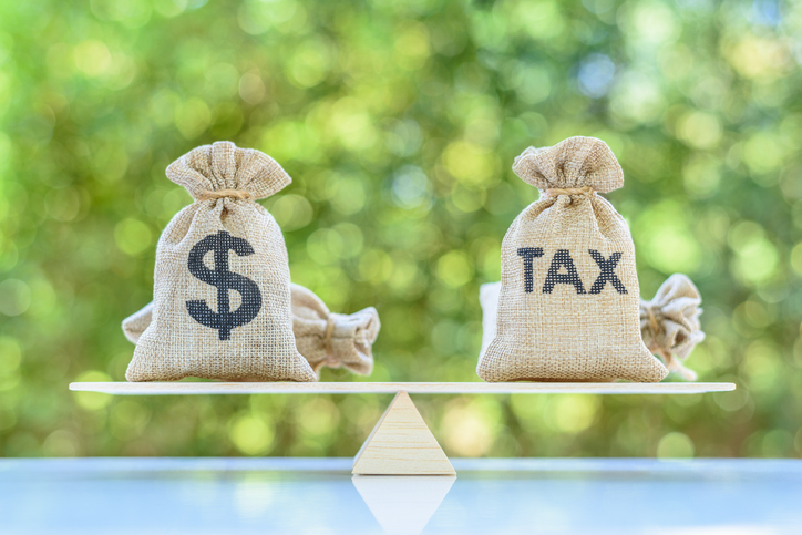 Money bags labelled dollar and tax balanced on a seesaw, symbolising how Australian income tax affects earnings for first‑time lodgers Money bags labelled dollar and tax balanced on a seesaw, symbolising how Australian income tax affects earnings for first‑time lodgers